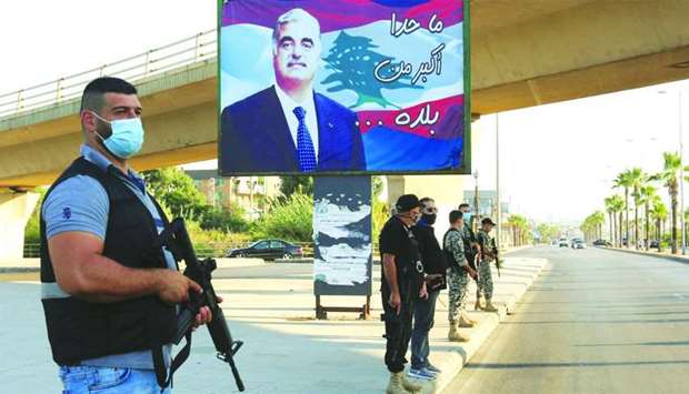 Members of security forces stand guard yesterday near a billboard depicting Lebanon's former Prime Minister Rafik al-Hariri, who was killed in a 2005 suicide bombing in southern Lebanon