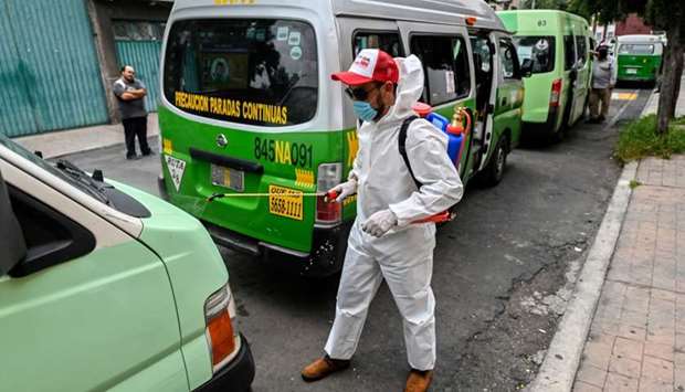 A cleaning worker wearing personal protective equipment (PPE) disinfects a public tranport vans in Mexico City