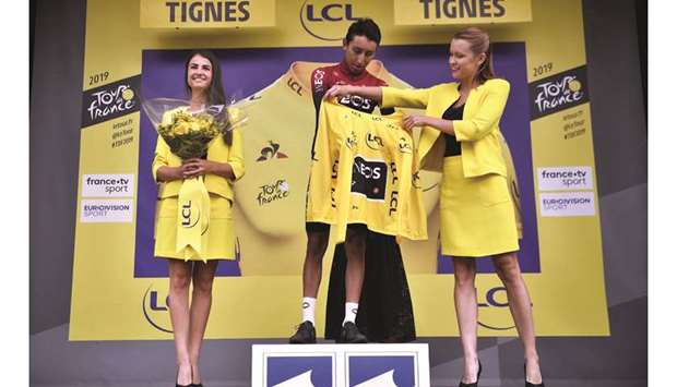In this July 26, 2019, picture, Colombiau2019s Egan Bernal (centre) is helped by hostesses to put on the yellow jersey on the podium of the 19th stage of the 106th edition of the Tour de France in Tignes. (AFP)