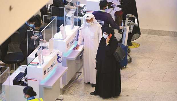 Travellers wearing face masks due to the novel coronavirus pandemic wait at a registering counter at the Kuwait International Airport, in Farwaniya, yesterday.