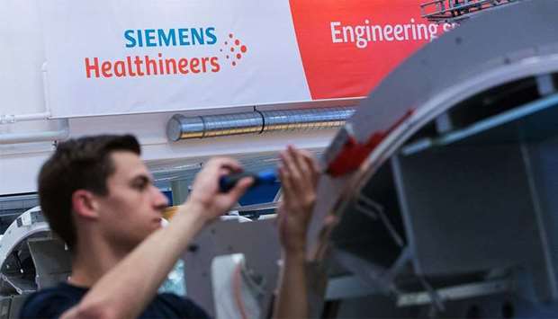 An employee works on the gantry of a Siemens Somatom computerised tomography (CT) scanner machine on the assembly line at the Siemens Healthineers factory in Forchheim, Germany.