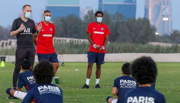 Cyril Klosek (L), technical director at the Paris Saint-Germain (PSG) Football Academy in Doha, speaks with the academy players during a training session on Saturday