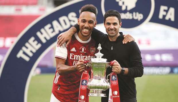 Arsenalu2019s striker Pierre-Emerick Aubameyang (left) and head coach Mikel Arteta hold the winneru2019s trophy after winning the FA Cup final against Chelsea at Wembley Stadium in London on Saturday. (AFP)