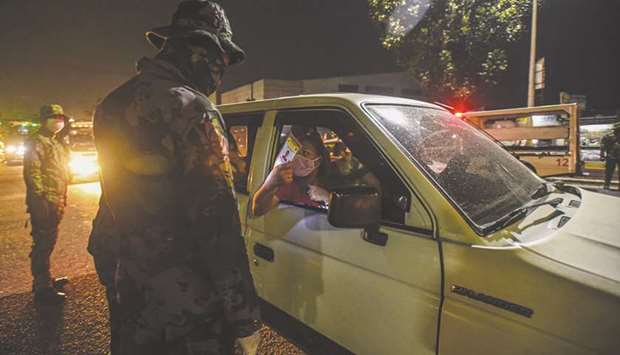 File photo taken on March 15, 2020 shows members of the police and the army randomly inspect vehicles at a check point coming from North Luzon Expressway in Manila during the implementation of measures to limit the spread of Covid-19, the new coronavirus.