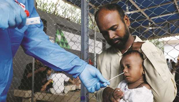 A healthcare worker takes a swab sample from a child to be tested for the coronavirus in Karachi.