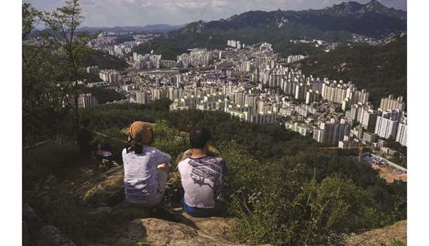 Hikers sit at a viewpoint overlooking the Seoul city skyline yesterday. South Korea ramped up coronavirus restrictions to try to contain a growing outbreak, as many countries around the world battled worrying surges in infections.