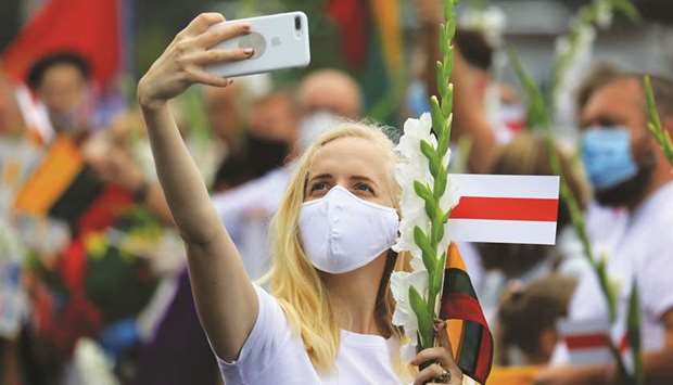 A woman takes a selfie while holding a Belarussian opposition flag as people form a human chain from Vilnius to Medininkai, along the Lithuanian border with Belarus.