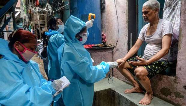Health workers wearing Personal Protective Equipments (PPE) use a fingertip pulse oximeter and check the body temperature of a resident inside the Dharavi slum during a door-to-door COVID-19 coronavirus screening in Mumbai