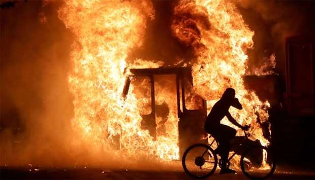 A man on a bike rides past a city truck on fire outside the Kenosha County Courthouse in Kenosha, Wisconsin, U.S., during protests following the police shooting of Black man Jacob Blake