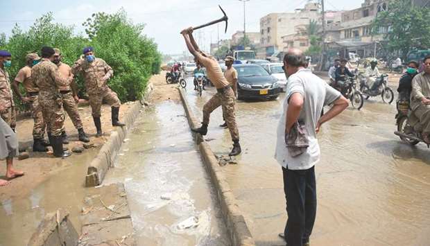 An army soldier works to clear a blocked drain in a flooded area following heavy monsoon rains in Karachi.