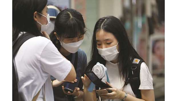 Students wearing masks look at a mobile phone amid the coronavirus pandemic in Seoul, South Korea, yesterday.