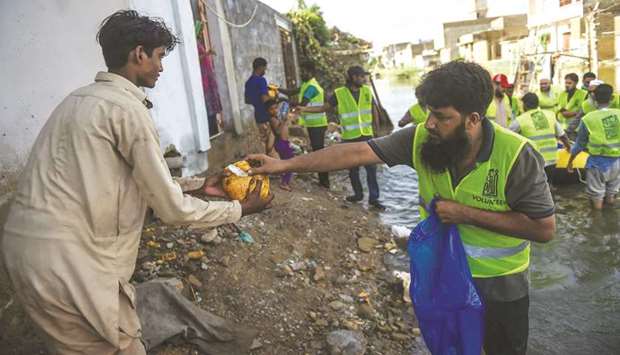Volunteers distribute food to residents at a flooded area in Karachi yesterday.