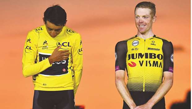 In this July 28, 2019, picture, Colombiau2019s Egan Bernal (left) listens to his national anthem after receiving his overall leaderu2019s yellow jersey as third-placed Netherlandsu2019 Steven Kruijswijk looks on on the podium of the 106th Tour de France at Champs-Elysees in Paris, France. (AFP)