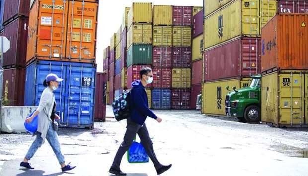 Pedestrians walk past shipping containers at Ray-mont Logistiques in Montreal. Export and import volumes fell sharply (-18.4% and -22.6%, respectively) in Canada as trading partners' economies also shrank owing to their own measures to combat Covid-19 outbreaks.