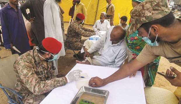 Members of an army medical team provide treatment to flood-affected people at a camp in Karachi.
