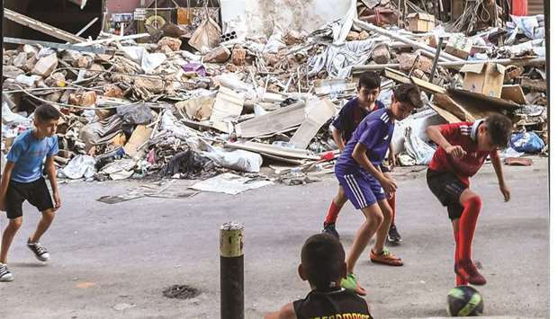 Children play with a football past rubble and destruction along a street in the Gemmayzeh district of Lebanonu2019s capital Beirut yesterday, in the aftermath of the monster blast at the nearby port which devastated the city.