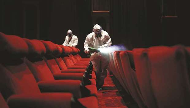 Workers wearing protective gear spray disinfectant inside an empty PVR multiplex that was closed following the outbreak of the coronavirus disease, in New Delhi.