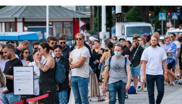 A man wearing a protective face mask walking next to travellers as they queue up to board a boat at Stranvagen in Stockholm, amid the novel coronavirus