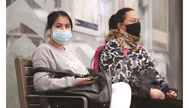 People wearing face masks wait for a bus on the first day of New Zealandu2019s new coronavirus disease safety measure that mandates wearing of a mask on public transport, in Auckland, New Zealand.