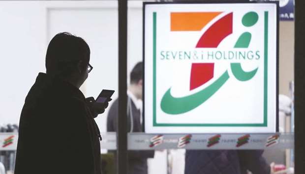 A pedestrian is silhouetted while walking past a 7-Eleven convenience store, operated by Seven & i Holdings Co, at night in Tokyo. Seven & i Holdings has agreed to buy Marathon Petroleum Corpu2019s gas-station business, adding 3,900 Speedway outlets to clinch a dominant position of almost 14,000 stores in the US and Canada.