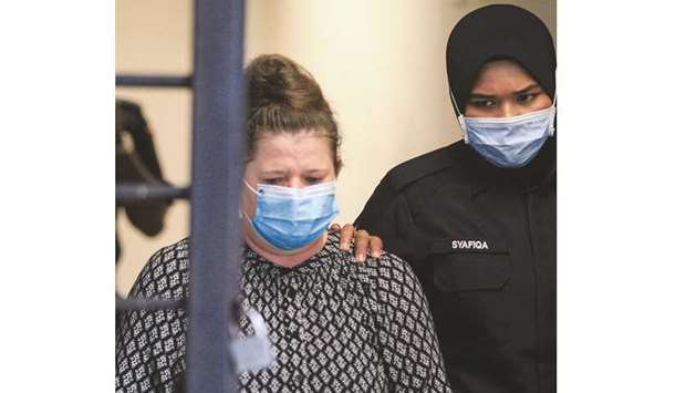 British national Samantha Jones, accused of killing her husband in 2018, is escorted by a police officer to a van after appearing in court in Alor Setar, in northern Malaysia, yesterday.