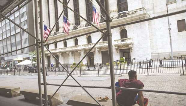 A man sits on a bench outside the New York Stock Exchange. Blue-chip US companies are slowing down on borrowing after months of massive bond sales and hanging onto the money theyu2019ve raised to insulate themselves from the pandemic.