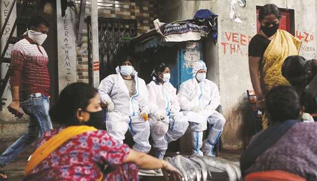 Health workers in personal protective equipment rest during a check up campaign for the coronavirus disease at a slum in Mumbai, yesterday.