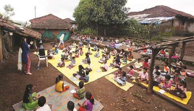 Children, who have missed their online classes due to a lack of Internet facilities, maintain a safe distance as they listen to pre-recorded lessons over loudspeakers, after schools were closed following the coronavirus disease outbreak, in Dandwal village in Maharashtra.