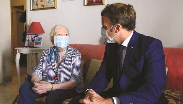 French President Emmanuel Macron (right) pays a visit to Gisele Charles, 80, who lives alone in Toulon, southern France, yesterday, as part of meetings with home-care assistants. Emmanuel Macron announced that the state would release 80mn euros to pay, with an equal contribution from the departments, an exceptional Covid-19 bonus for home carer.