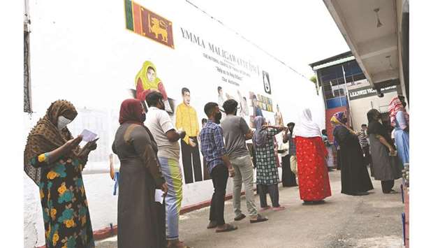 Voters wait in a queue to cast their ballots in the parliamentary election at a polling station in Colombo.
