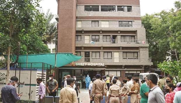Police officers and relatives stand outside a hospital where a fire broke out inside an intensive care unit treating patients infected with coronavirus in Ahmedabad yesterday.