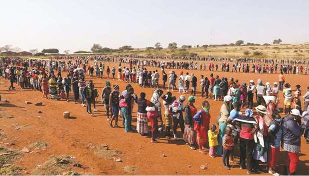 FILE PHOTO: People stand in a queue to receive food aid amid the spread of the coronavirus disease (Covid-19), at the Itireleng informal settlement, near Laudium suburb in Pretoria, South Africa, on May 20.