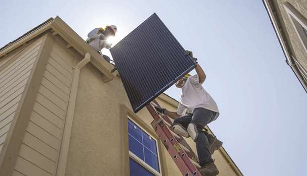 Contractors move a SunRun solar panel up a ladder to the roof of a new home in Sacramento, California (file). Even as the pandemic continues to drive down consumer spending and depress oil prices, investors are spending big on clean-tech companies.