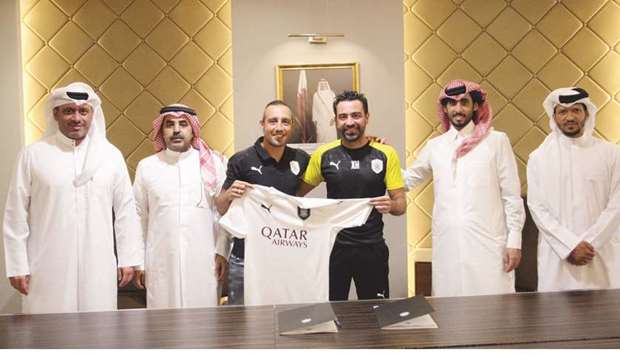 Santi Cazorla (centre) poses with Al Saddu2019s head coach Xavi Hernandez (second from right) and other club officials after signing a two-year contract.