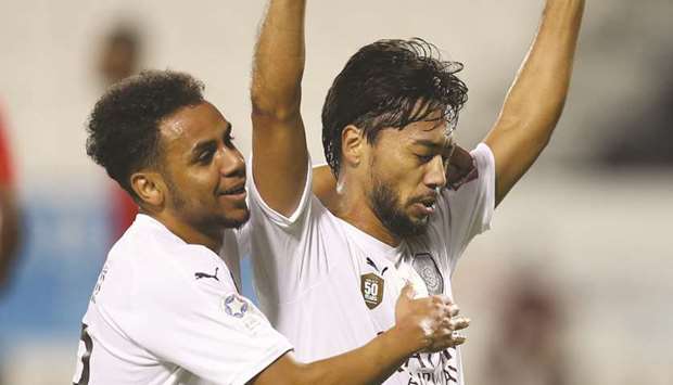 Al Saddu2019s Rodrigo Tabata (R) celebrates after scoring against Al Duhail. At right Al Sadd coach Xavi reacts during the match.