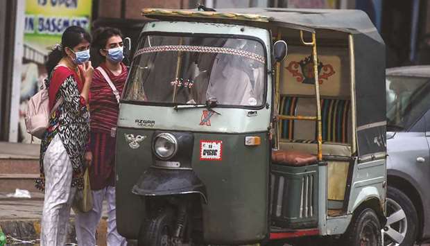 Women wearing face masks are seen speaking with an auto-rickshaw driver in Karachi. Data has revealed that among women infected with the coronavirus, those from the age group of 21-30 years were most affected.
