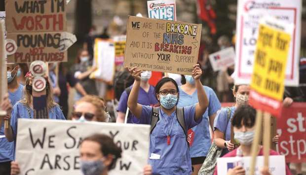 NHS workers hold placards as they march through the streets of London yesterday.