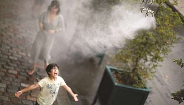 A child cools off under a water spray yesterday amid a heatwave in Paris.