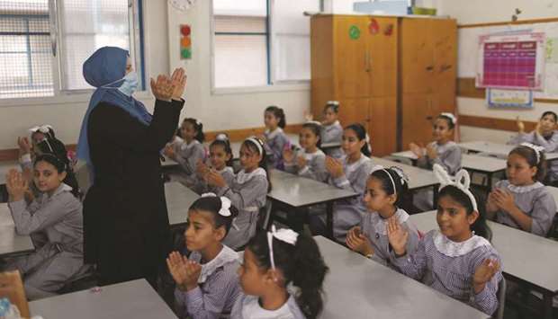 A teacher wearing a protective face mask gestures as Palestinian students sit in a classroom at a United Nations-run school as the new school year begins amid concerns about the spread of the coronavirus disease (Covid-19), in Gaza City, yesterday.