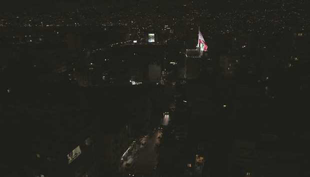 A Lebanese flag flutters near unlit residential buildings during a partial blackout in Beirut.