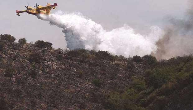 A firefighting airplane is seen in action as a wildfire burns in the Monte Catillo nature reserve in Tivoli, near Rome.