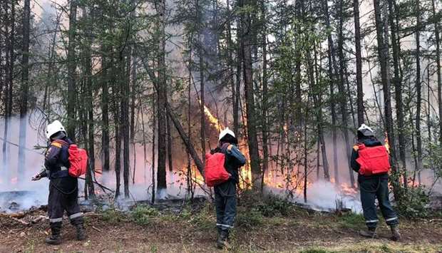 This handout photograph released by the Russian Emergency Situations Ministry on August 13, 2021, shows Emergency Situations Ministry firefighters as they extinguish a forest fire outside Yakutsk.