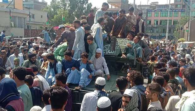 Taliban fighters and local people sit on an Afghan National Army (ANA) humvee vehicle on a street in Jalalabad province on August 15, 2021.