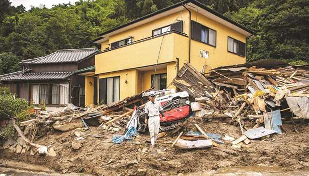 A construction company employee works among debris in front of a house at the site of a landslide caused by heavy rain in Kanzaki City, Saga Prefecture, yesterday.