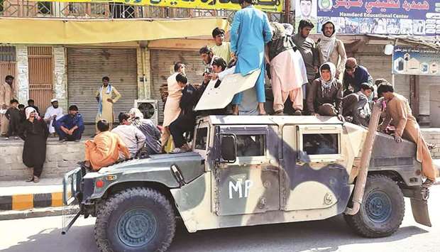 BACK IN BUSINESS: Taliban fighters and local residents sit over an Afghan National Army humvee vehicle along the roadside in Laghman province yesterday. (AFP)