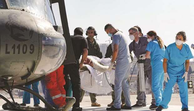 A man with severe burn injuries sustained in the fuel tank explosion is carried on a stretcher from a helicopter after being transported for treatment at the severe burns unit of the Geitaoui hospital in Beirut yesterday. (AFP)
