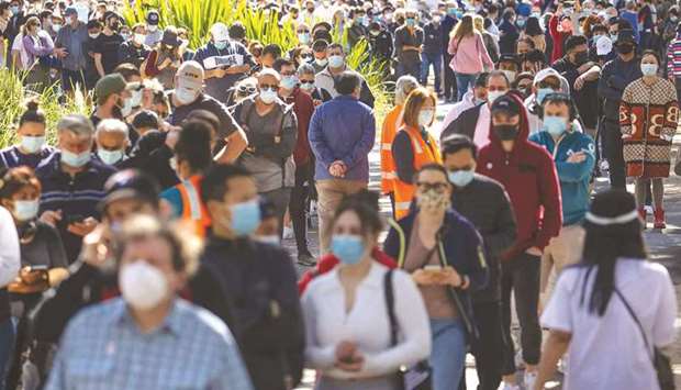 People wearing face masks stand in a line as they wait to be vaccinated at the Sydney Olympic Park Vaccination Centre at Homebush in Sydney yesterday.