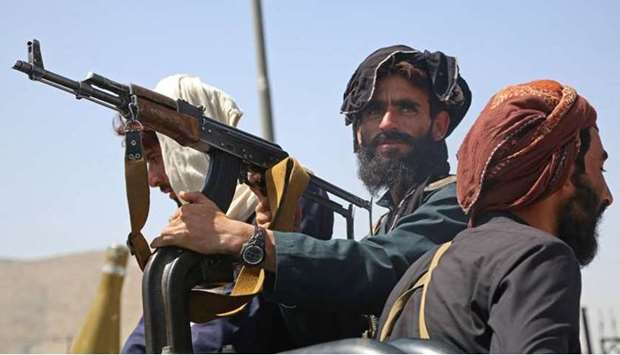 Taliban fighters stand guard in a vehicle along the roadside in Kabul.