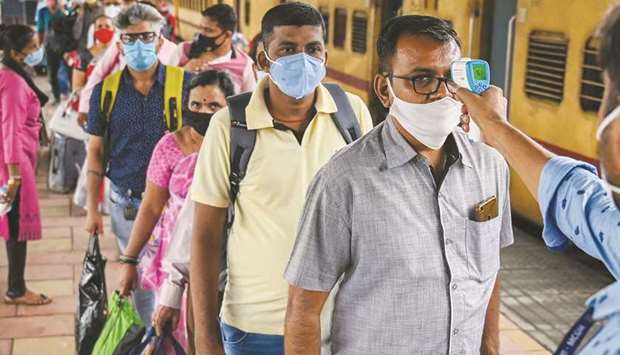 Passengers queue up to get their temperature checked for Covid-19 symptoms after arriving at a railway platform on a long distance train, in Mumbai yesterday.