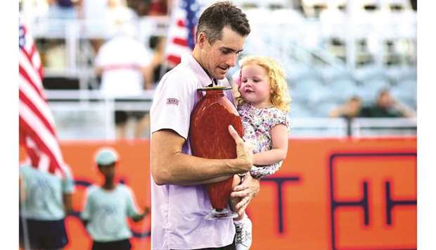 John Isner of the United States holds his daughter, Hunter Grace, in one arm and the winneru2019s trophy in the other after winning the Truist Atlanta Open in Atlanta, Georgia, United States, on Sunday. (AFP)